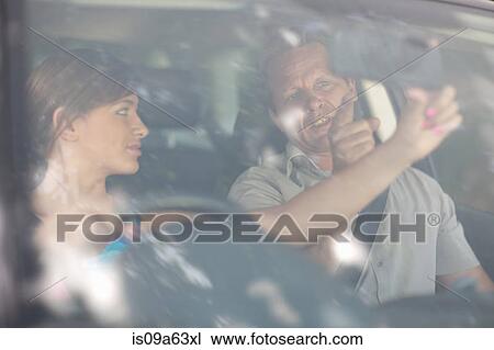 Stock Image - Father teaching teenage daughter driving. Fotosearch