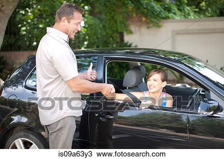 Stock Image - Father teaching teenage daughter driving. Fotosearch