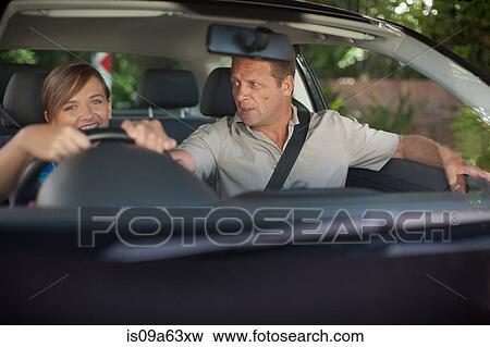 Stock Photo - Father teaching teenage daughter driving. Fotosearch