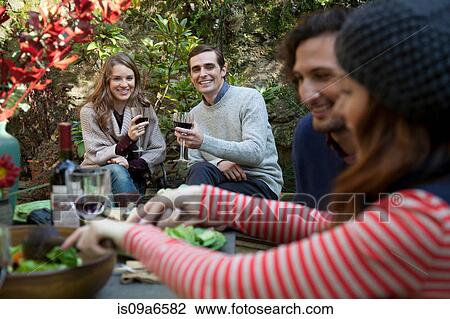 Stock Image - Friends eating together outdoors. Fotosearch