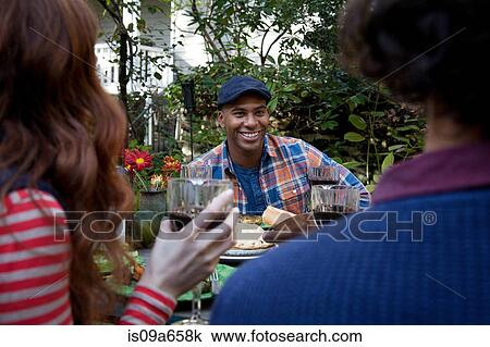 Stock Image - Friends eating together outdoors. Fotosearch
