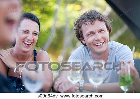 Stock Photo - Friends having drinks at table outdoors. Fotosearch