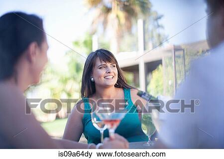 Stock Photo - Friends having drinks at table outdoors. Fotosearch