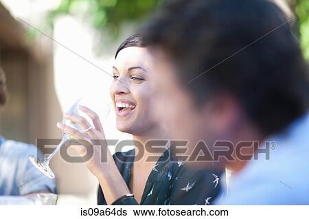 Stock Photograph - Friends having drinks at table outdoors. Fotosearch