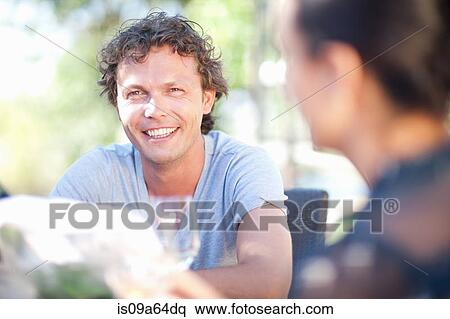 Stock Photography - Friends having drinks at table outdoors. Fotosearch