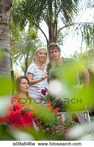 Stock Photo - Friends shopping for plants in nursery. Fotosearch
