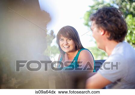 Stock Photo - Friends sitting at table outdoors. Fotosearch