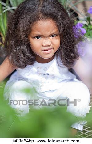 Frowning girl sitting in plants View Large Photo Image Stock Photography - Frowning girl sitting in plants. Fotosearch