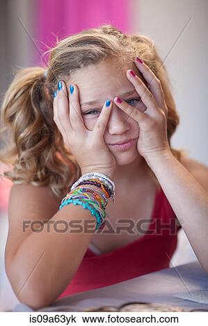 Stock Image - Frustrated girl with head in hands. Fotosearch