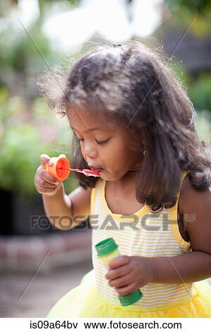 Stock Photo - Girl blowing bubbles outdoors. Fotosearch