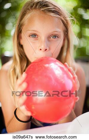 Girl blowing up balloon at party View Large Photo Image Stock Photograph - Girl blowing up balloon at party. Fotosearch
