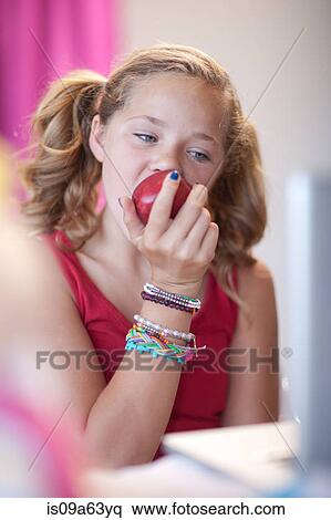 Girl eating apple at desk View Large Photo Image Stock Photography - Girl eating apple at desk. Fotosearch