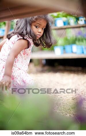 Picture - Girl examining flowers outdoors. Fotosearch