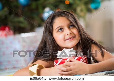 Stock Photo - Girl holding Christmas present on floor. Fotosearch