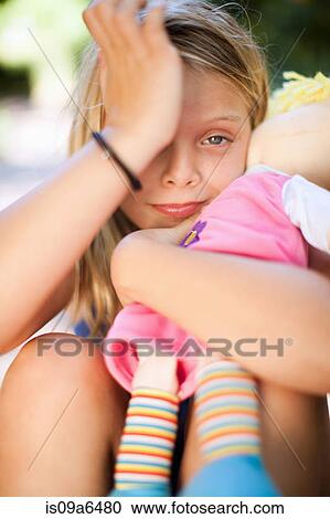 Stock Image - Girl holding doll outdoors. Fotosearch