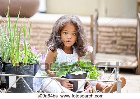 Stock Photograph - Girl holding potted plant at nursery. Fotosearch