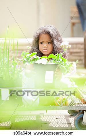 Stock Photograph - Girl holding potted plant at nursery. Fotosearch