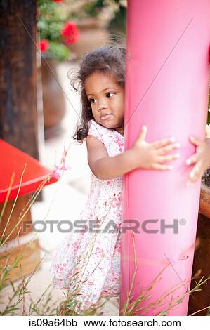 Stock Image - Girl hugging pole outdoors. Fotosearch