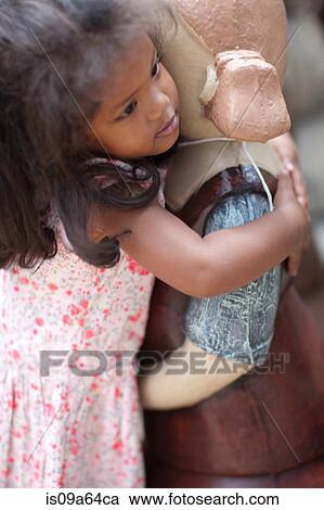 Stock Image - Girl hugging statue outdoors. Fotosearch