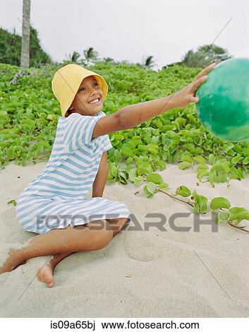 Stock Image - Girl playing with ball on beach. Fotosearch