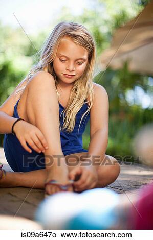 Girl putting on flip flop outdoors View Large Photo Image Picture - Girl putting on flip flop outdoors. Fotosearch