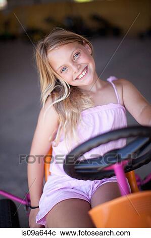 Stock Image - Girl riding go-kart in garage. Fotosearch
