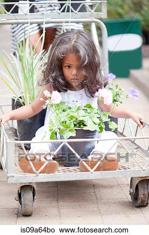 Girl sitting in cart at flower nursery View Large Photo Image Picture - Girl sitting in cart at flower nursery. Fotosearch