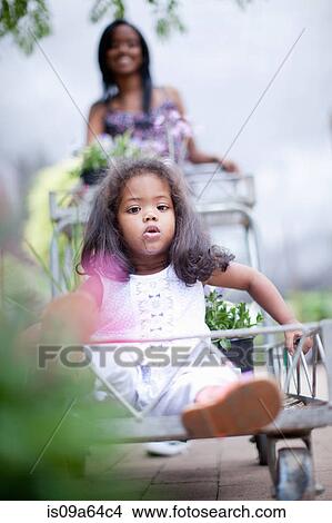 Girl sitting in cart at plant nursery View Large Photo Image Picture - Girl sitting in cart at plant nursery. Fotosearch