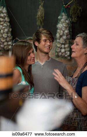 Stock Photo - Grocer helping couple in grocery store. Fotosearch