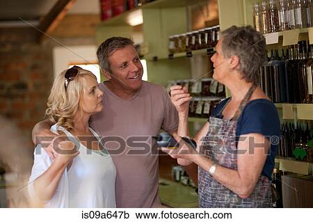 Stock Image - Grocer helping couple in store. Fotosearch