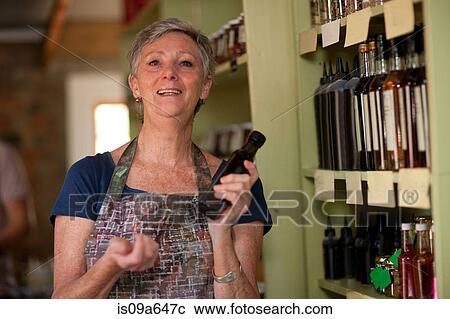 Grocer holding bottle of vinegar in shop View Large Photo Image Stock Image - Grocer holding bottle of vinegar in shop. Fotosearch
