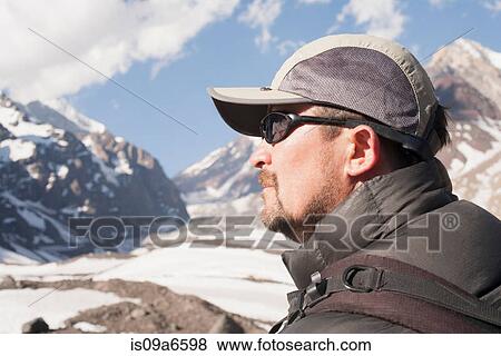 Stock Photo - Hiker overlooking snowy mountains. Fotosearch