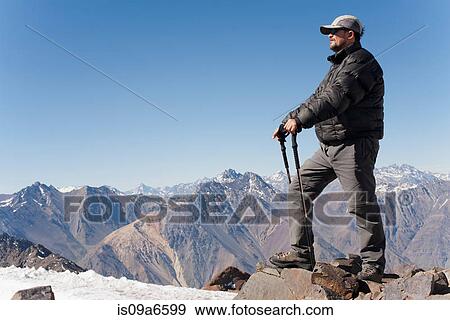 Stock Photo - Hiker overlooking snowy mountains. Fotosearch