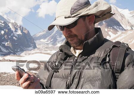 Stock Photo - Hiker with cell phone in snowy mountains. Fotosearch