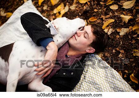 Picture - Man and dog hugging on picnic blanket. Fotosearch