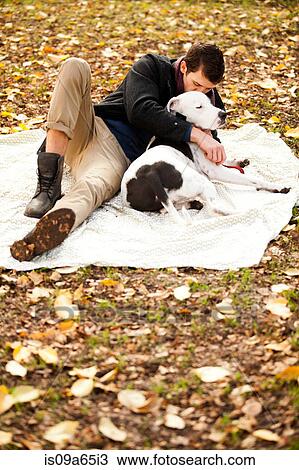 Stock Image - Man and dog relaxing on picnic blanket. Fotosearch