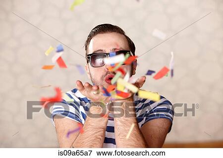Man blowing confetti at party View Large Photo Image Stock Photo - Man blowing confetti at party. Fotosearch