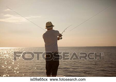 Stock Photo - Man fishing in still ocean. Fotosearch