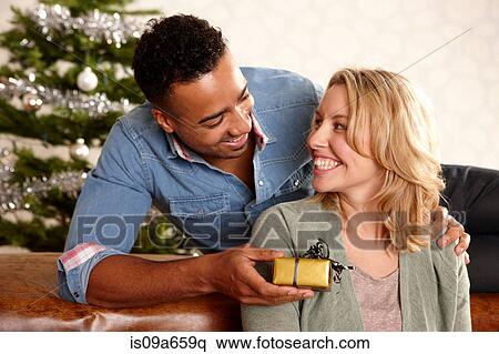 Stock Photography - Man giving girlfriend Christmas present. Fotosearch