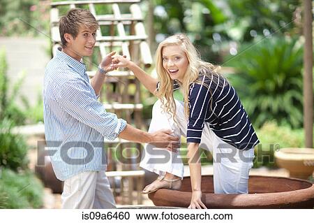 Stock Image - Man helping girlfriend out of planter. Fotosearch