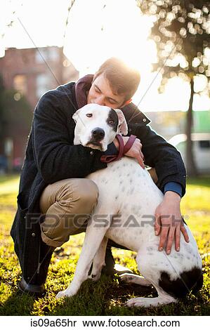 Stock Photography - Man hugging dog in park. Fotosearch