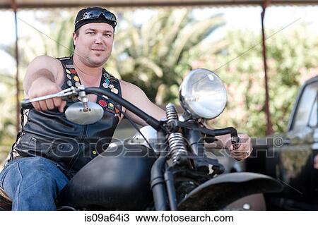 Stock Image - Man in leather vest on motorcycle. Fotosearch