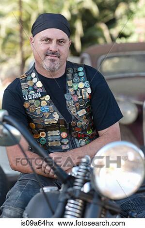 Stock Photo - Man in leather vest on motorcycle. Fotosearch