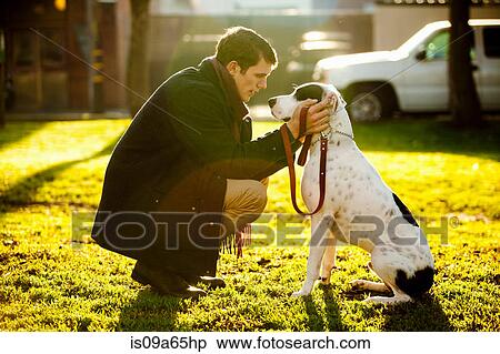 Stock Photography - Man petting dog in park. Fotosearch