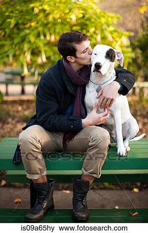 Stock Photo - Man petting dog on park bench. Fotosearch