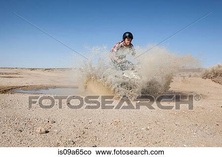 Picture - Man riding four-wheeler in desert. Fotosearch