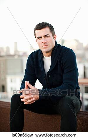 Stock Photo - Man sitting on urban balcony. Fotosearch