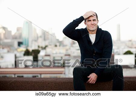 Stock Photo - Man sitting on urban balcony. Fotosearch