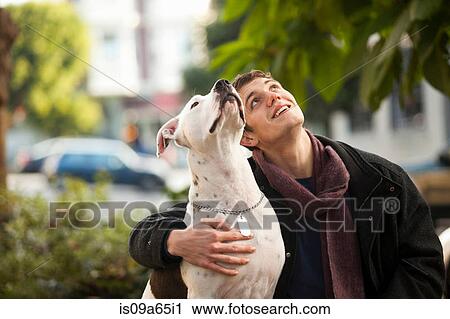 Stock Image - Man sitting with dog in park. Fotosearch