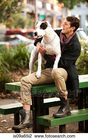 Man sitting with dog on picnic table View Large Photo Image Stock Image - Man sitting with dog on picnic table. Fotosearch